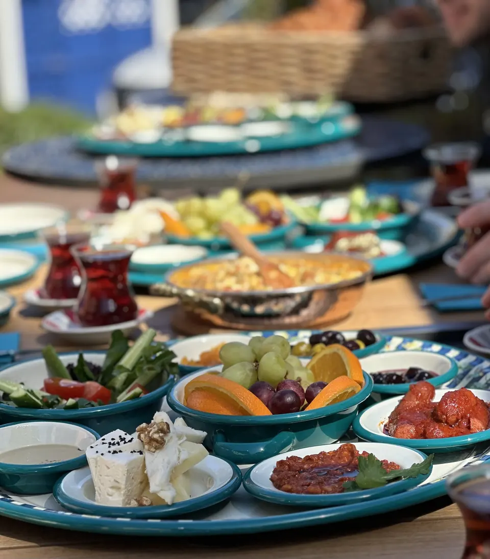 Traditional Turkish breakfast at Berna’s Bakery in Issaquah, featuring cheeses, olives, fresh fruit, salads, and Turkish tea served on turquoise plates.